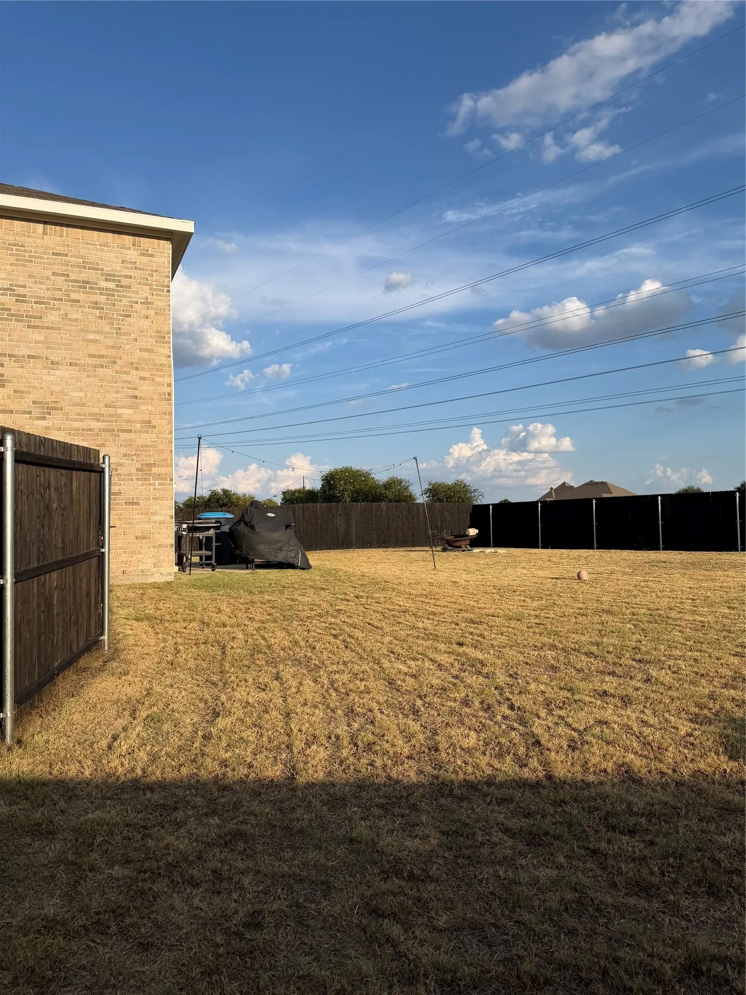 Expansive backyard featuring a wood-panel fence, brick exterior, and open green space