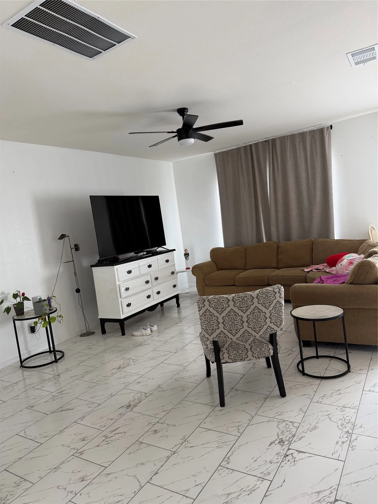 White tile flooring throughout, featuring a matte black ceiling fan and natural light from a window