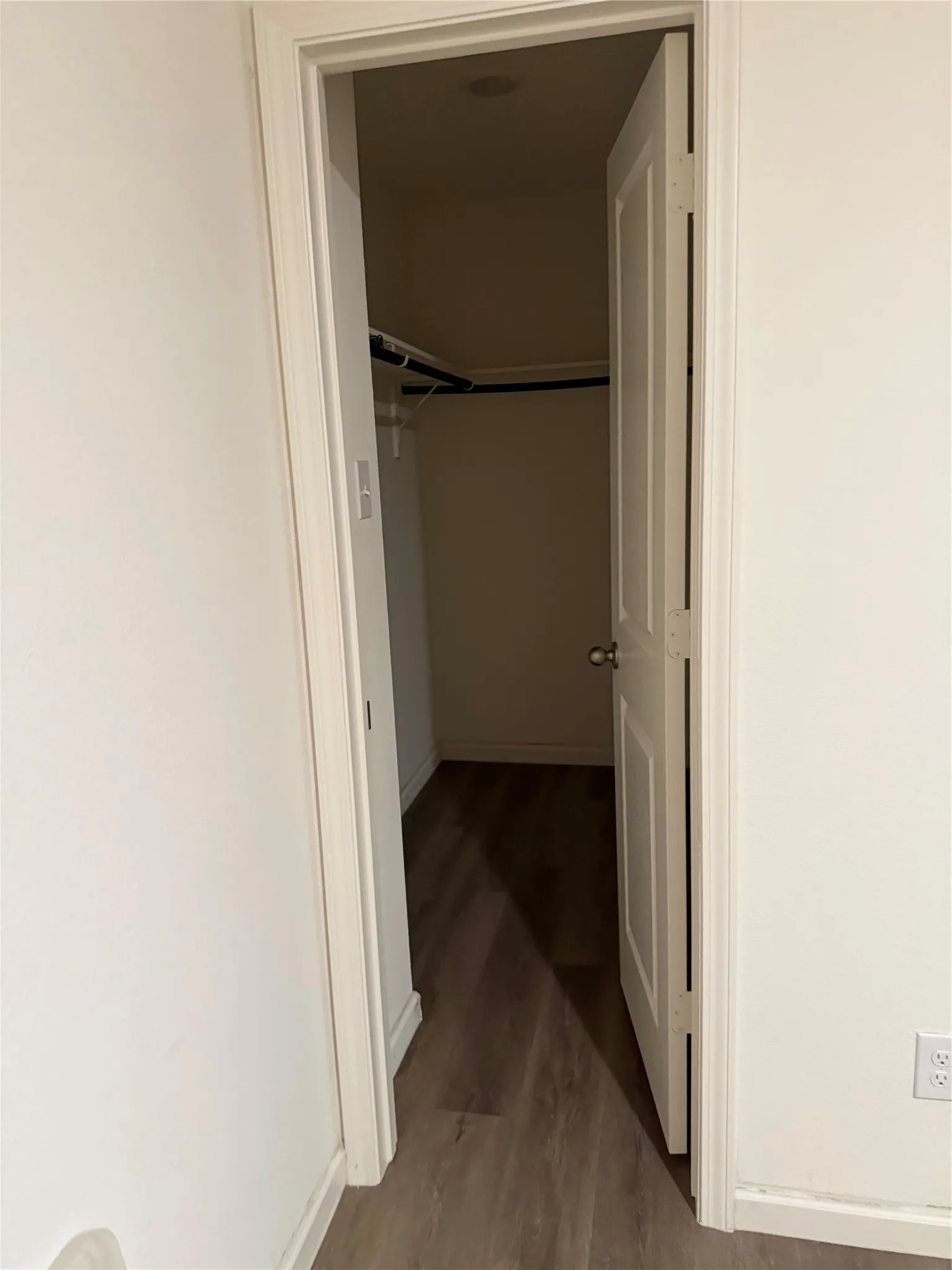 Wood-finish flooring extending into a closet space with built-in shelving and hanging rods