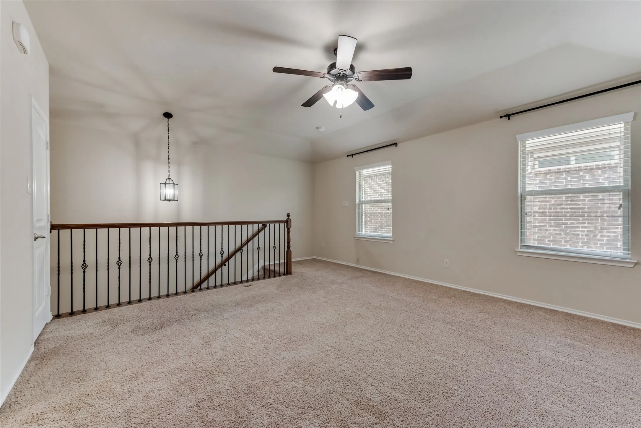 Empty room featuring light colored carpet, lofted ceiling, and ceiling fan
