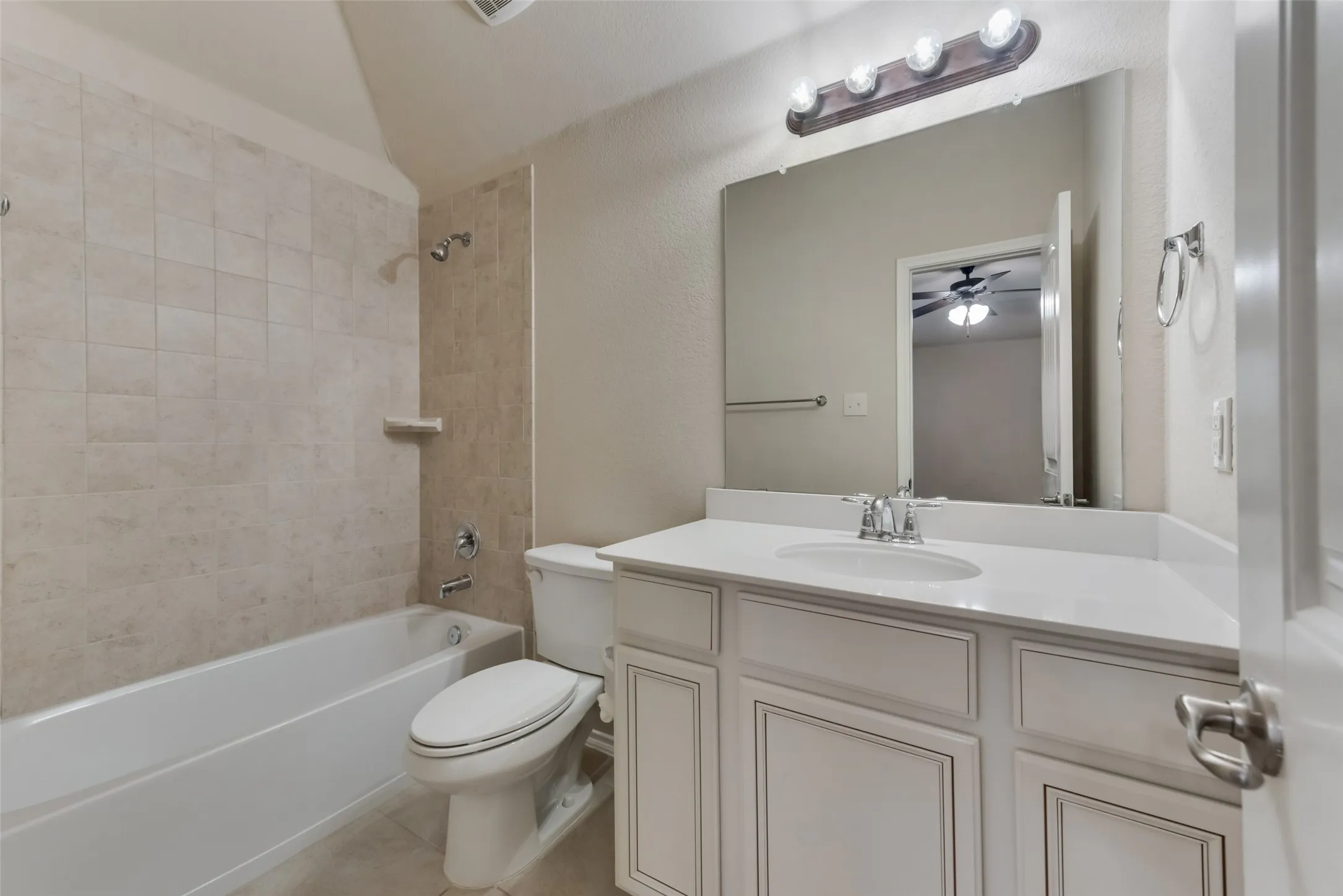 Full bathroom featuring vanity, tile patterned floors, ceiling fan, tiled shower / bath combo, and toilet