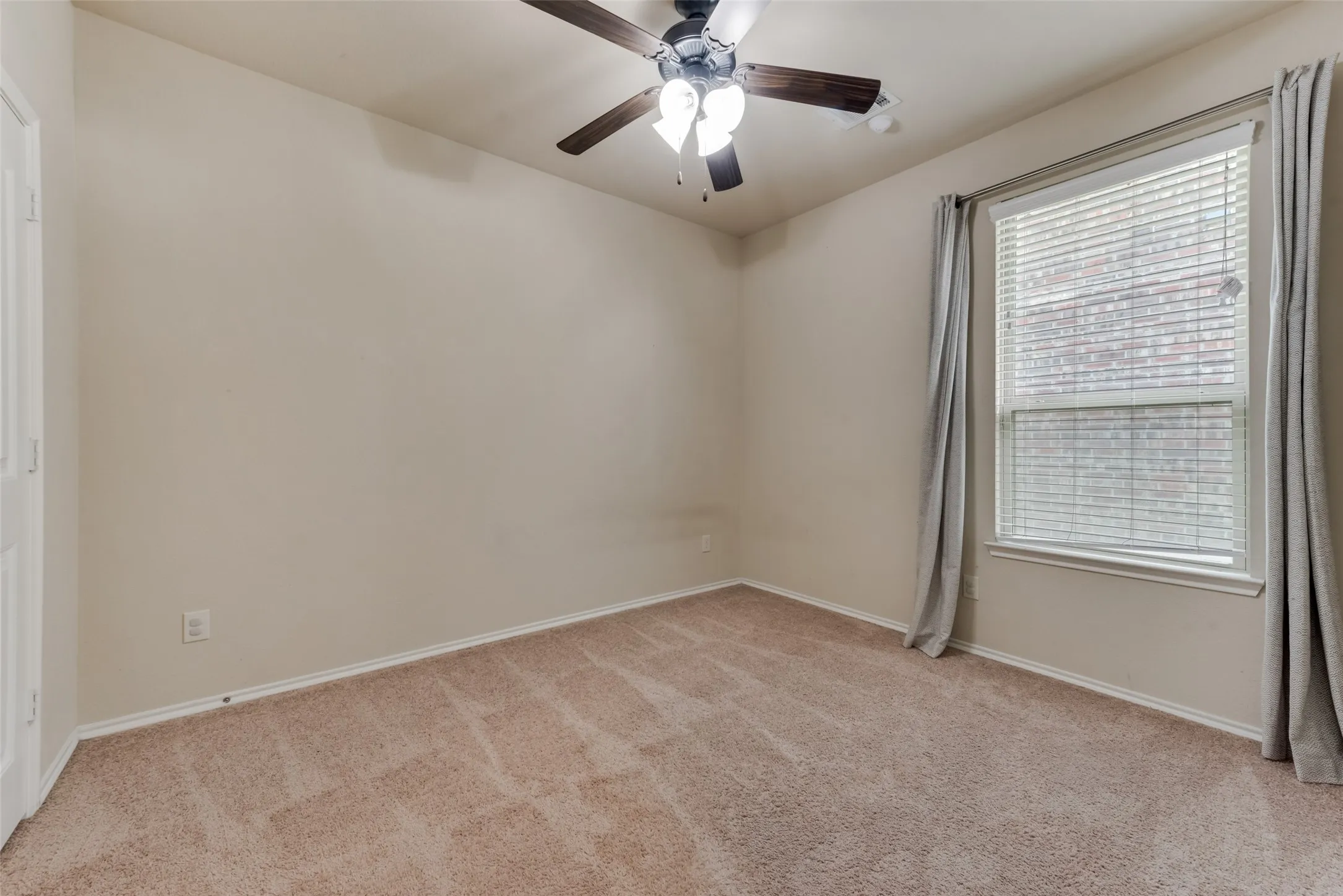 Spare room featuring light carpet and ceiling fan