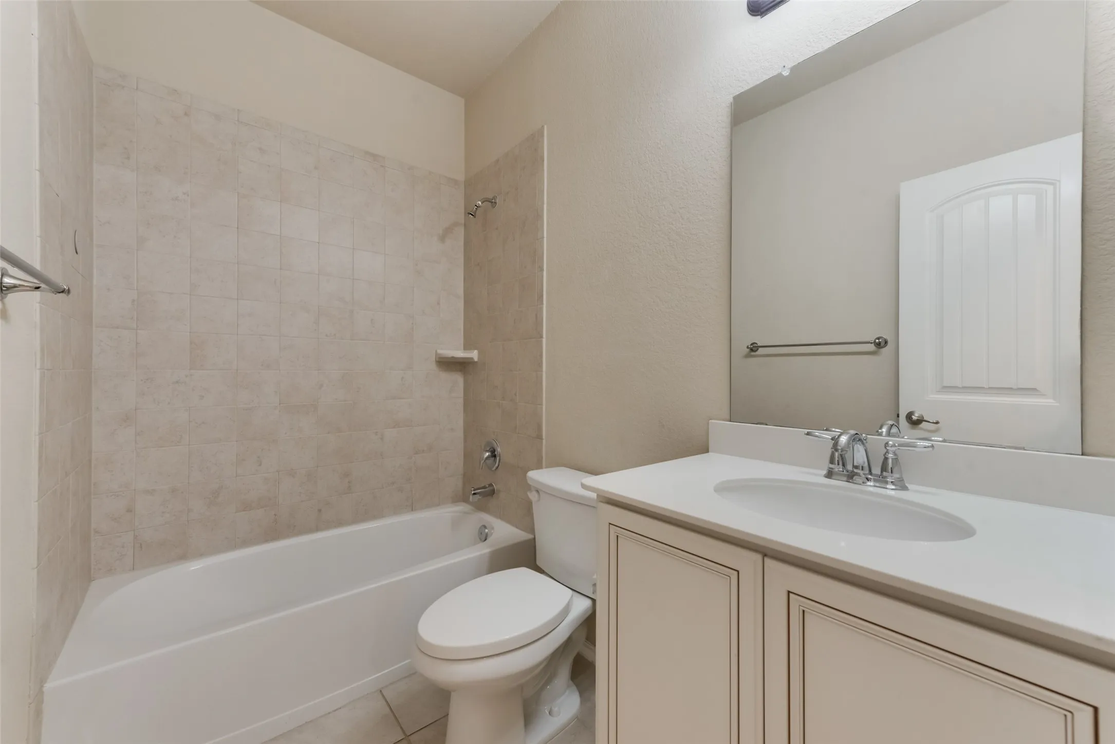 Full bathroom with toilet, tile patterned floors, tiled shower / bath combo, and vanity
