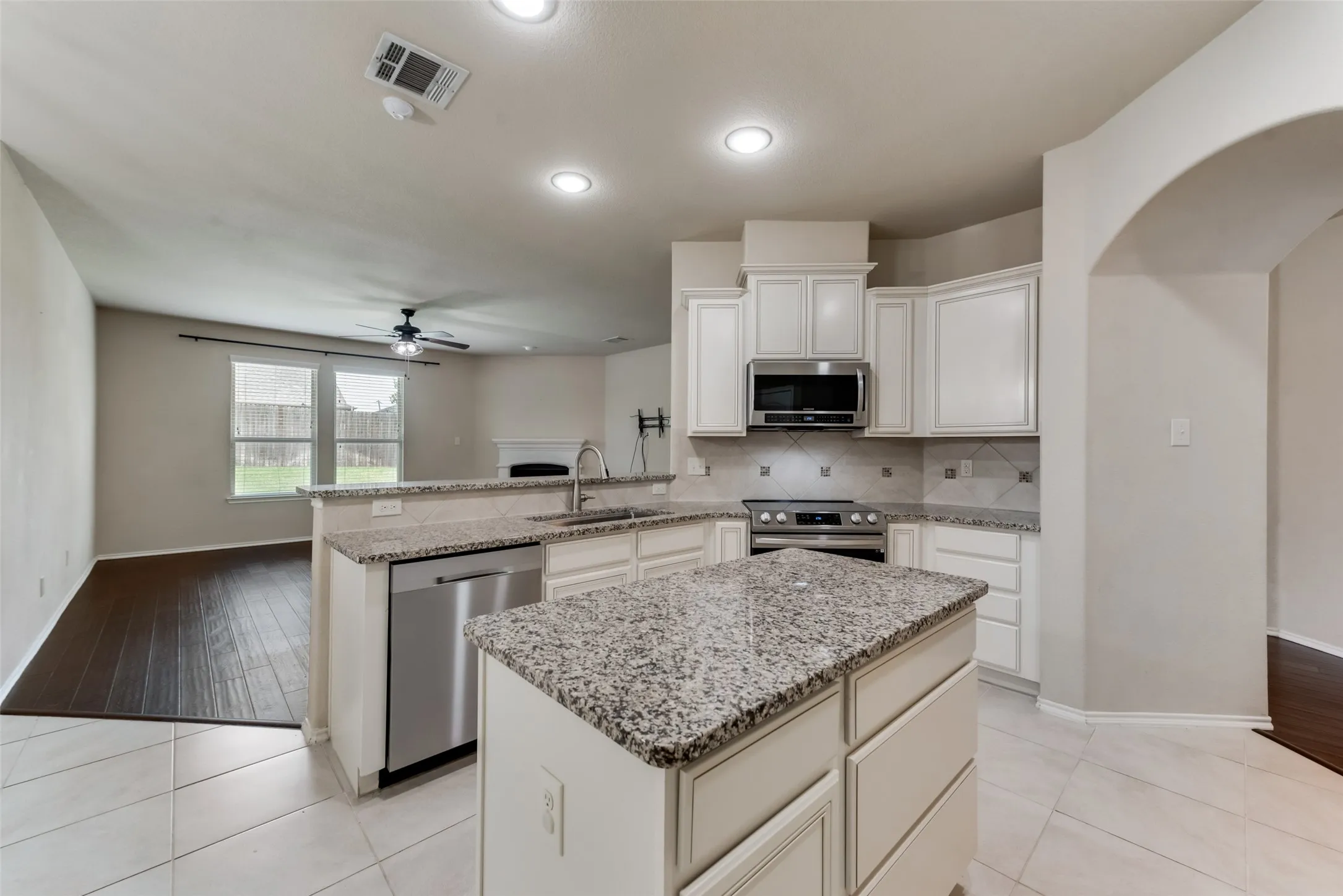Kitchen featuring ceiling fan, sink, light stone countertops, appliances with stainless steel finishes, and light hardwood / wood-style flooring