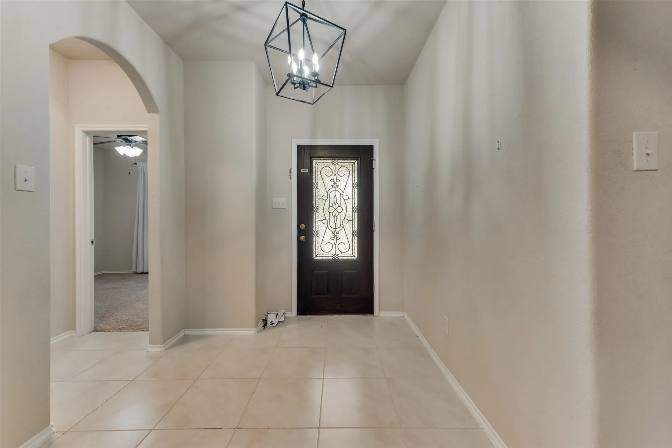 Entryway with ceiling fan with notable chandelier and light tile patterned floors