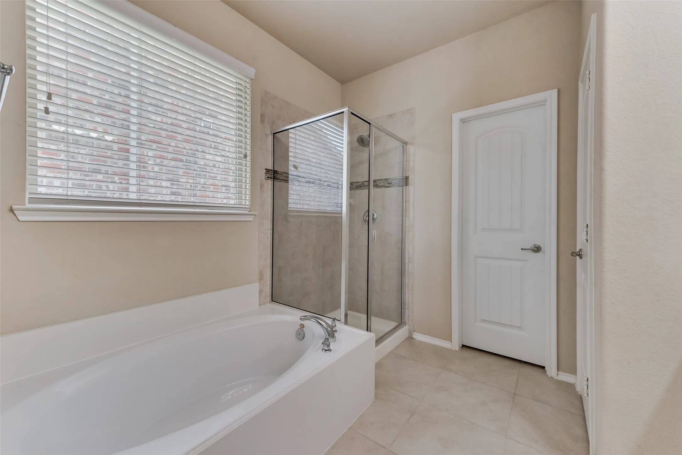 Bathroom featuring shower with separate bathtub and tile patterned flooring