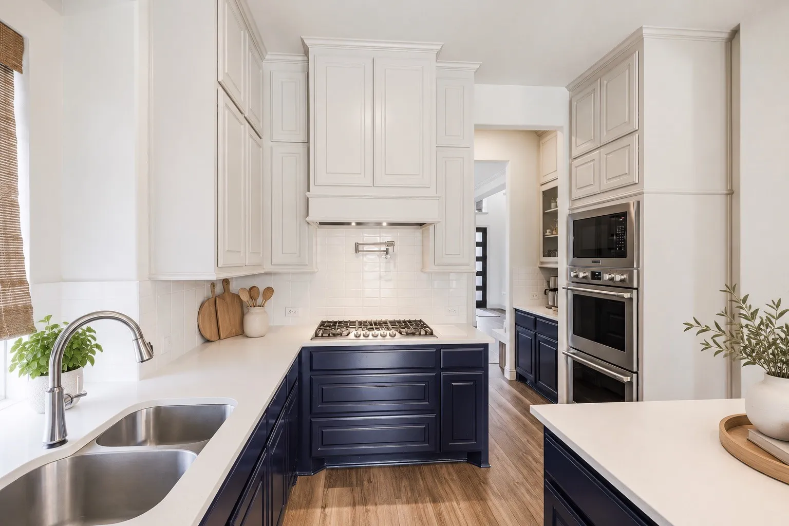 Dual-tone cabinetry, stainless steel double basin sink, gas cooktop, built-in stainless steel double ovens, and wood-finish flooring- staging with AI