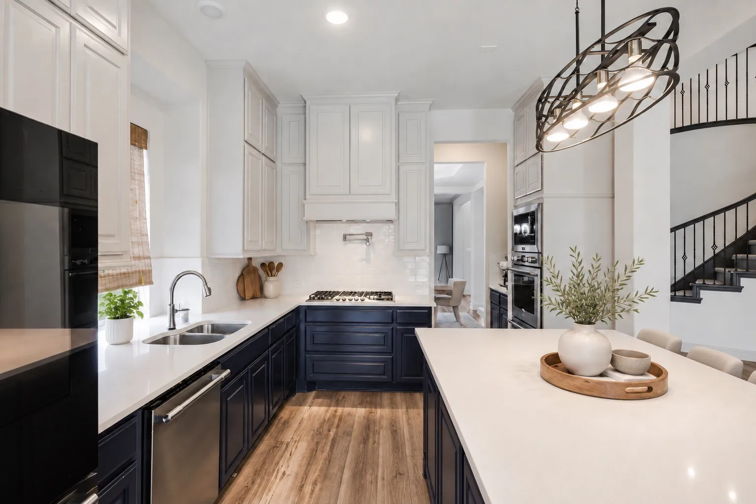 Two-tone cabinetry with white upper and dark lower cabinets, stainless steel appliances, wood-finish flooring, a kitchen island with seating, and a modern light fixture staging with AI
