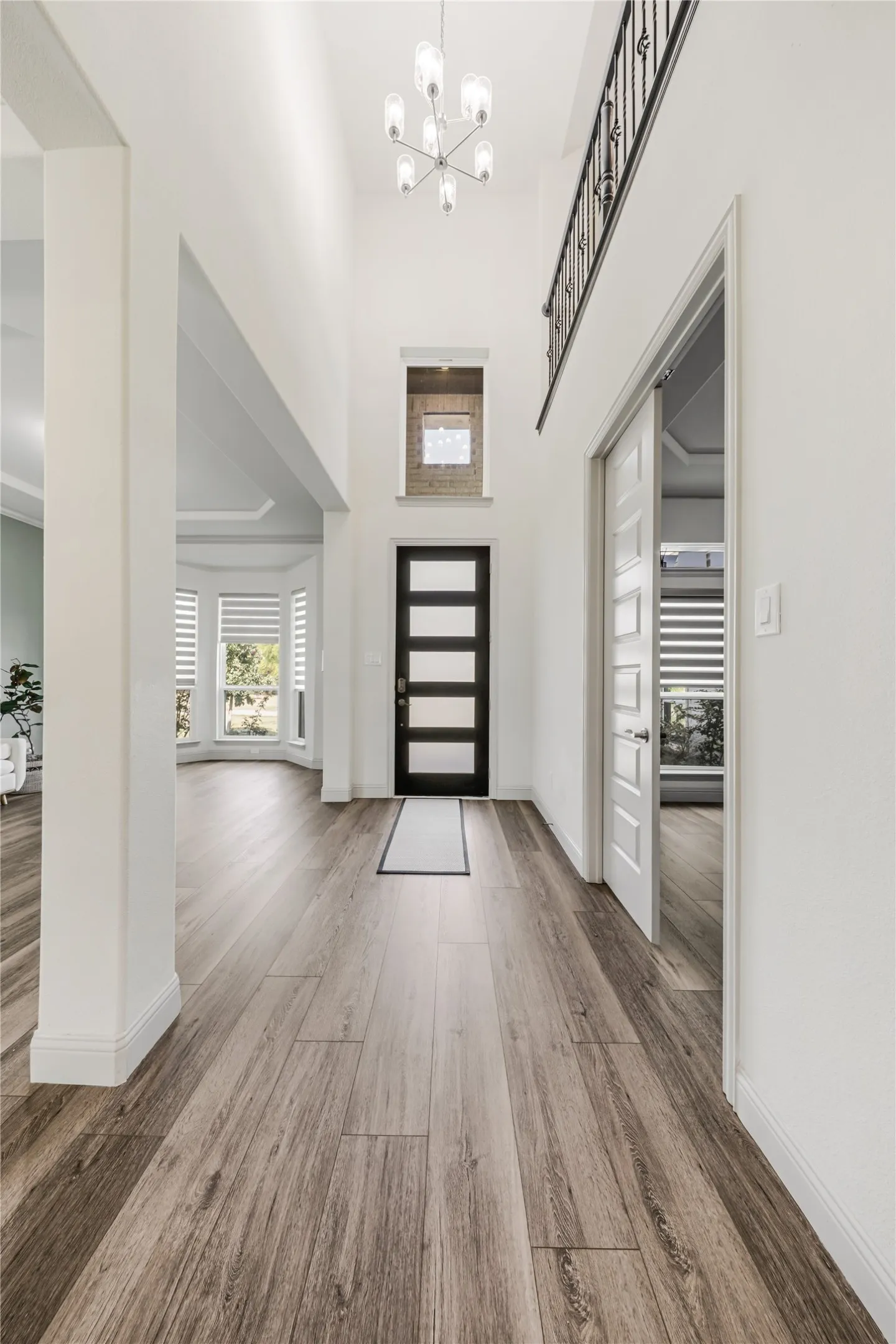Two-story foyer featuring wood-finish flooring, a modern chandelier, and a dark-paneled entry door