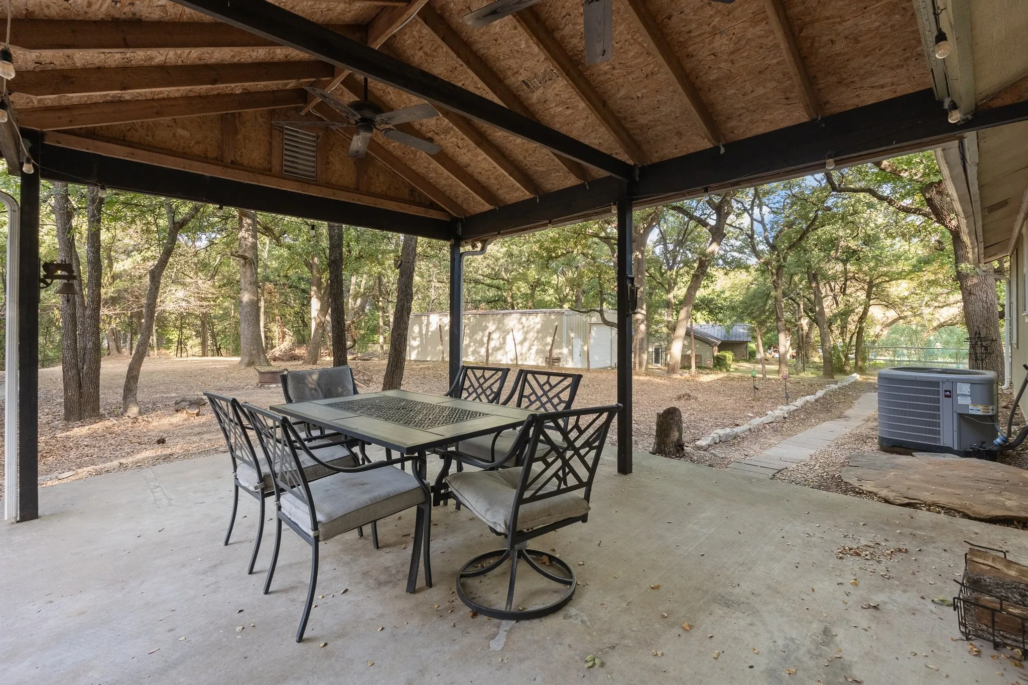Covered patio featuring a concrete slab, exposed wood beam ceiling, and a ceiling fan