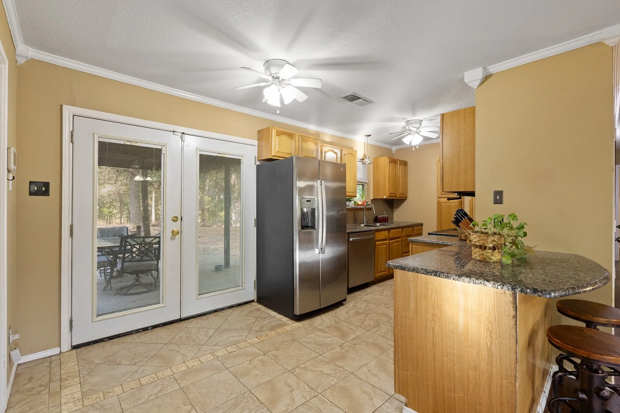 Kitchen featuring light wood cabinetry, stainless steel appliances, and tile flooring