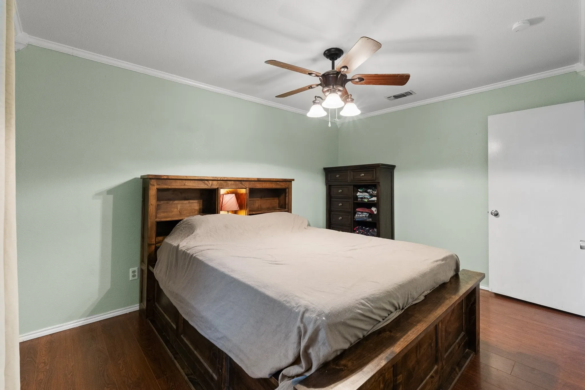 Wood-finish flooring with crown molding and a ceiling fan