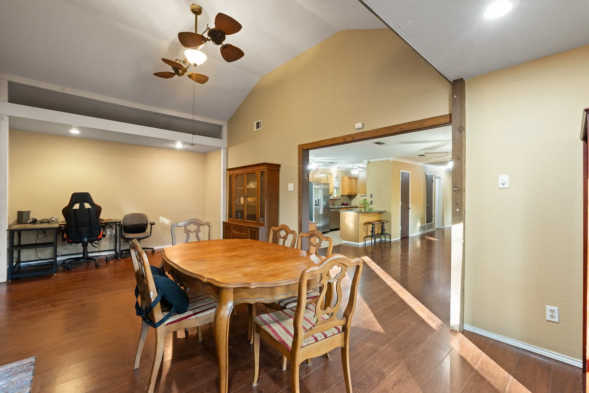 Vaulted ceiling with a ceiling fan, recessed lighting, wood-finish flooring