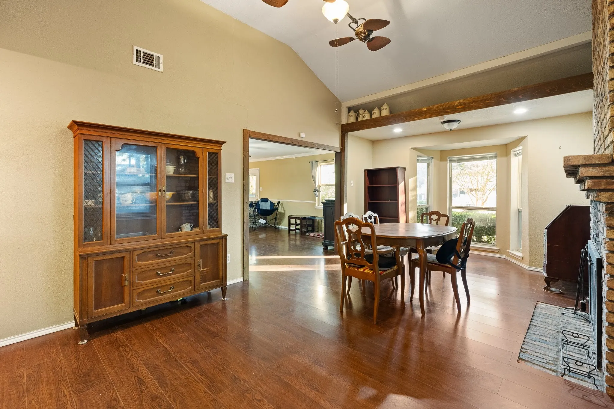 Vaulted ceiling, wood-finish flooring, bay window, recessed lighting, and brick fireplace