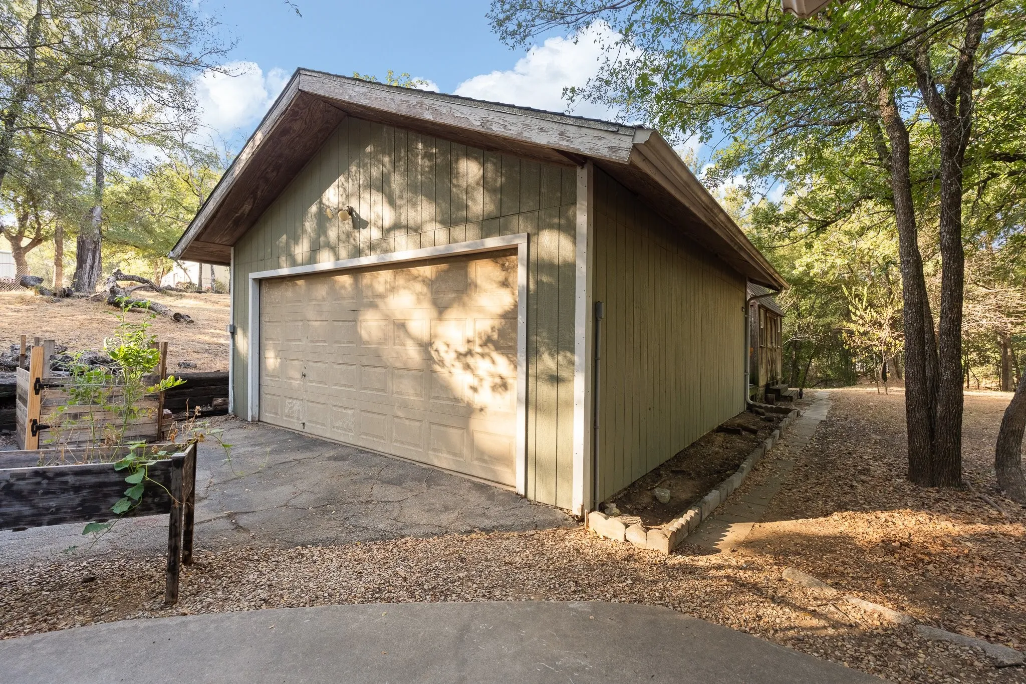 Detached garage with a paneled door, wood siding