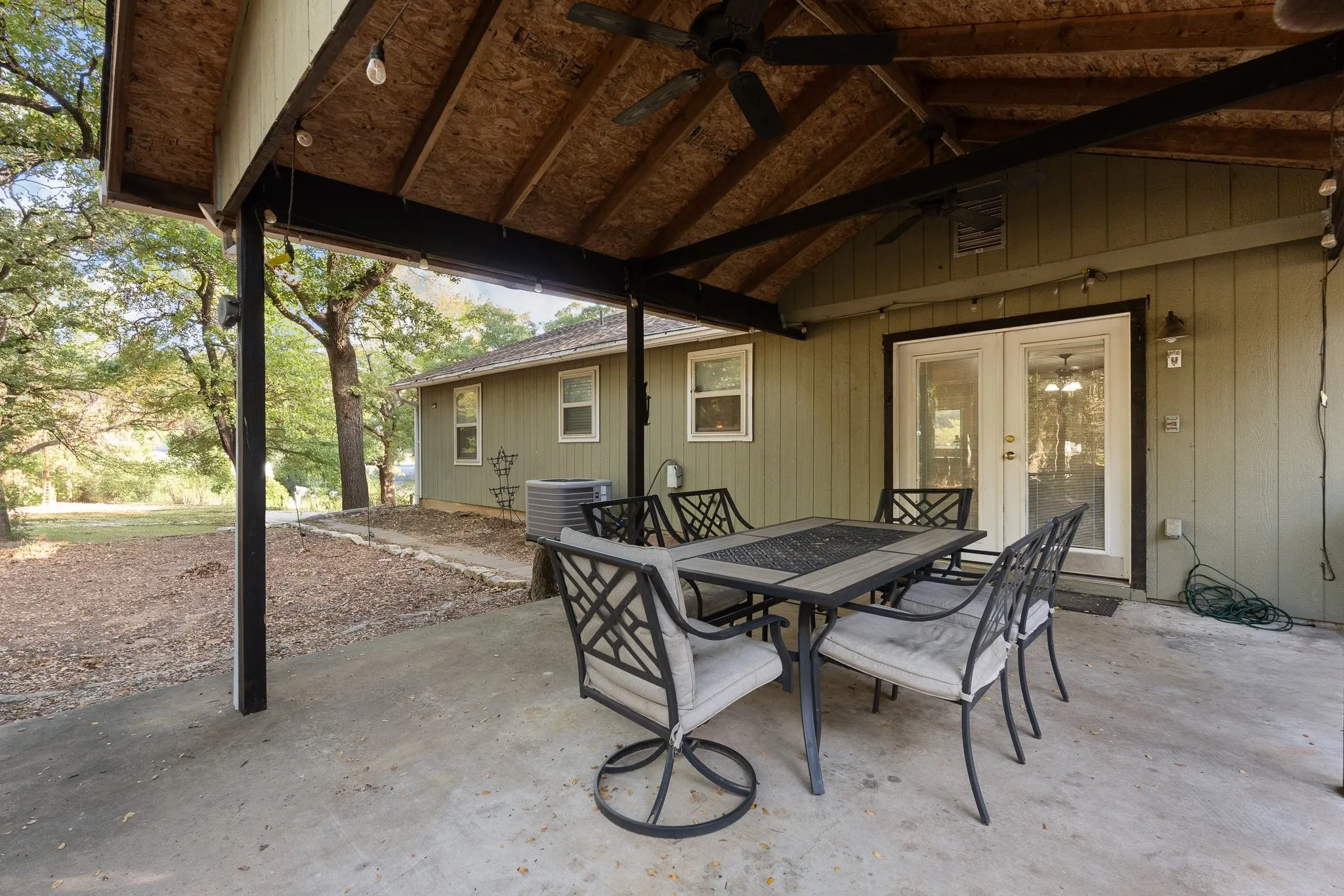 Covered patio with exposed wood ceiling and dual ceiling fans, featuring a concrete surface