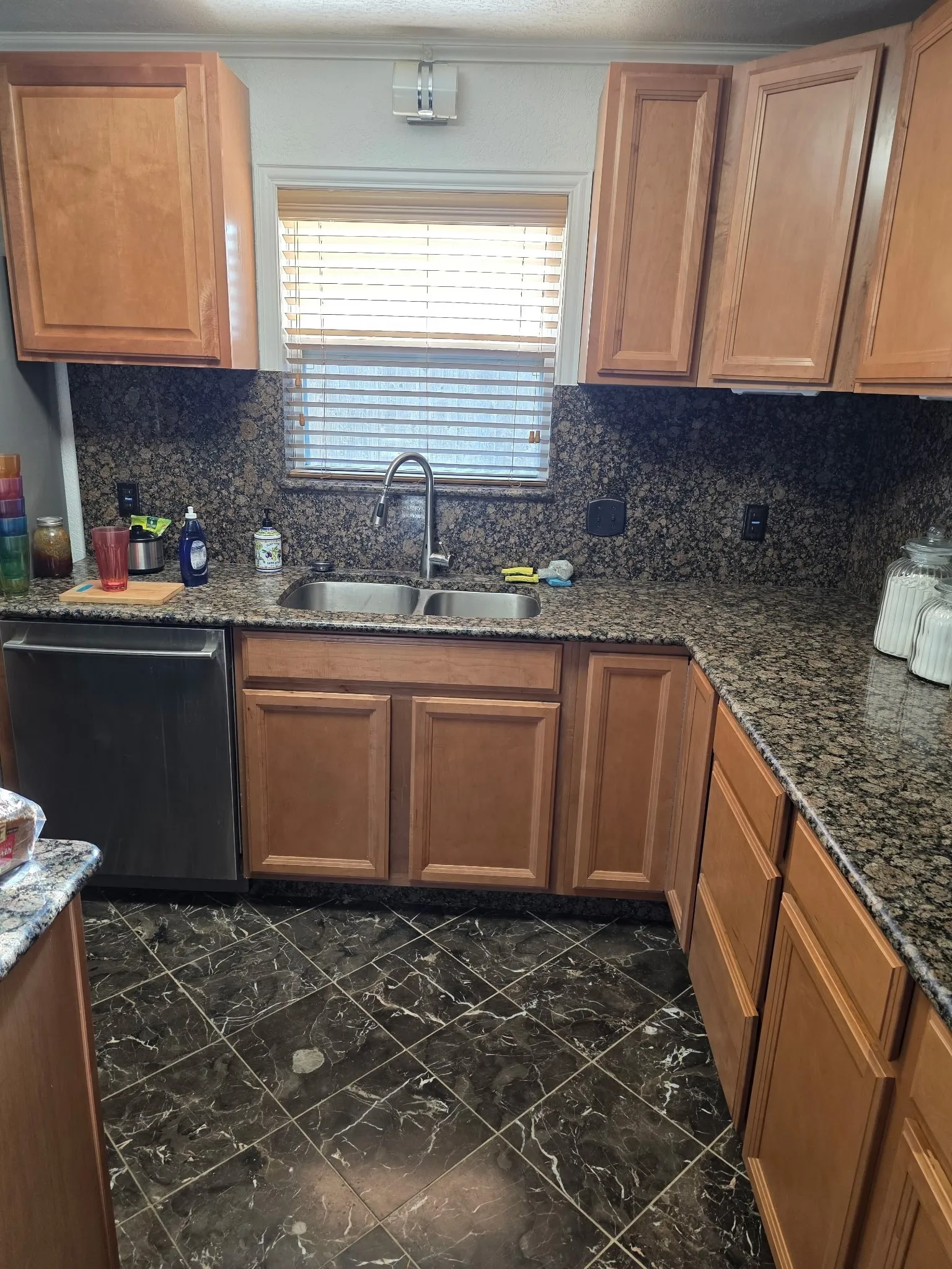 Kitchen featuring marble finish floor, decorative backsplash, a sink, and dishwasher