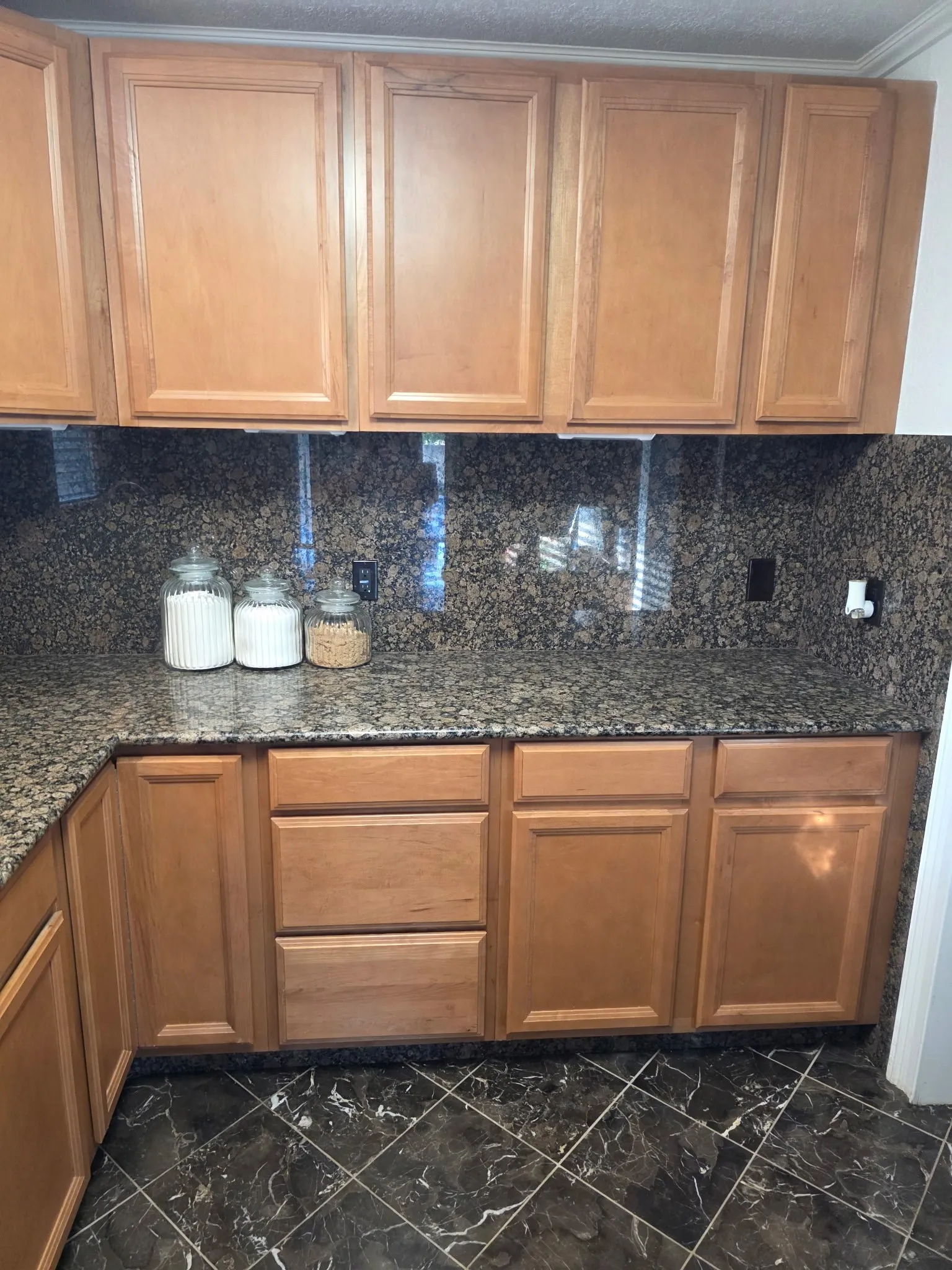 Kitchen featuring marble finish floor, dark stone counters, and decorative backsplash