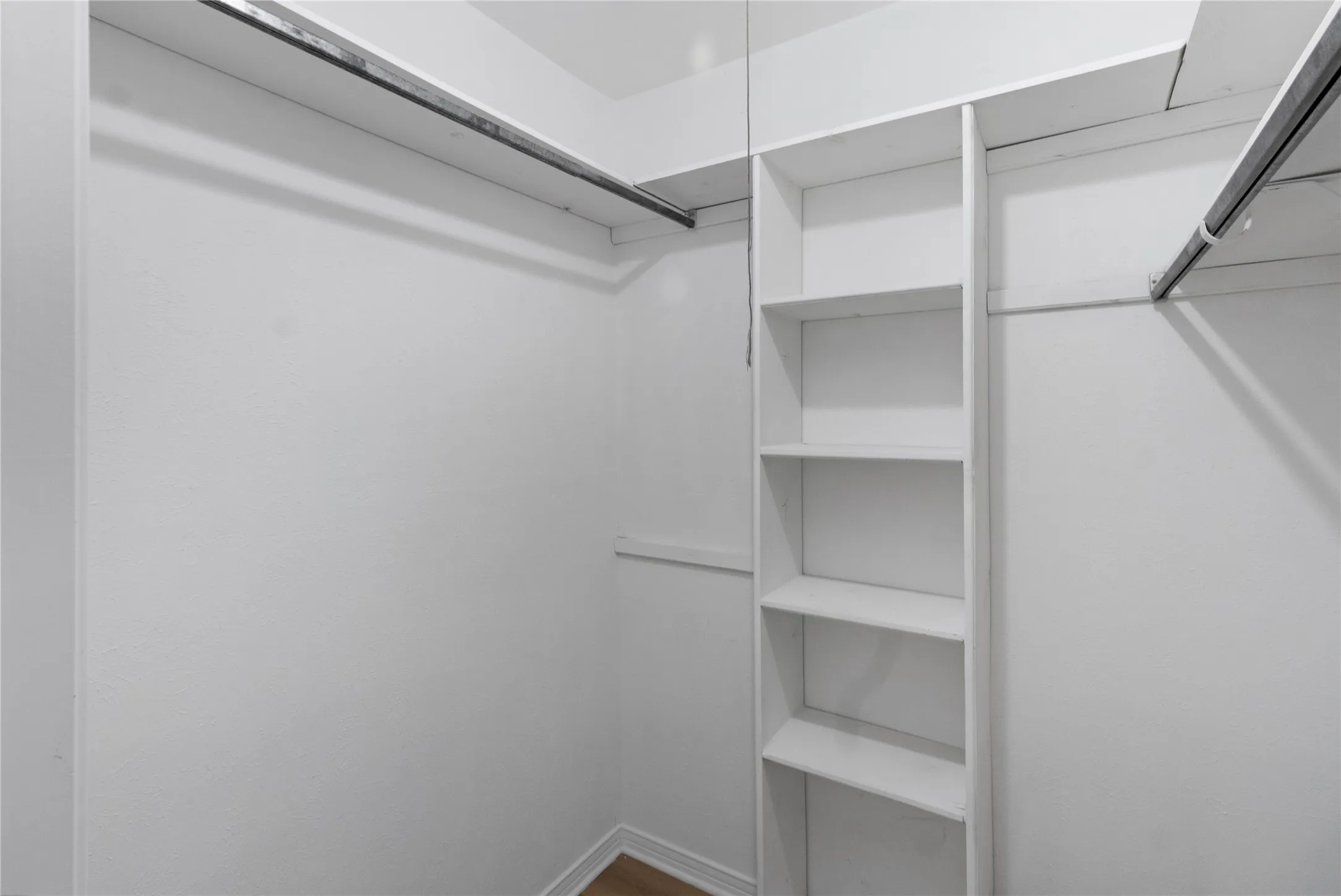 White built-in shelving, two hanging rods, and light-colored walls