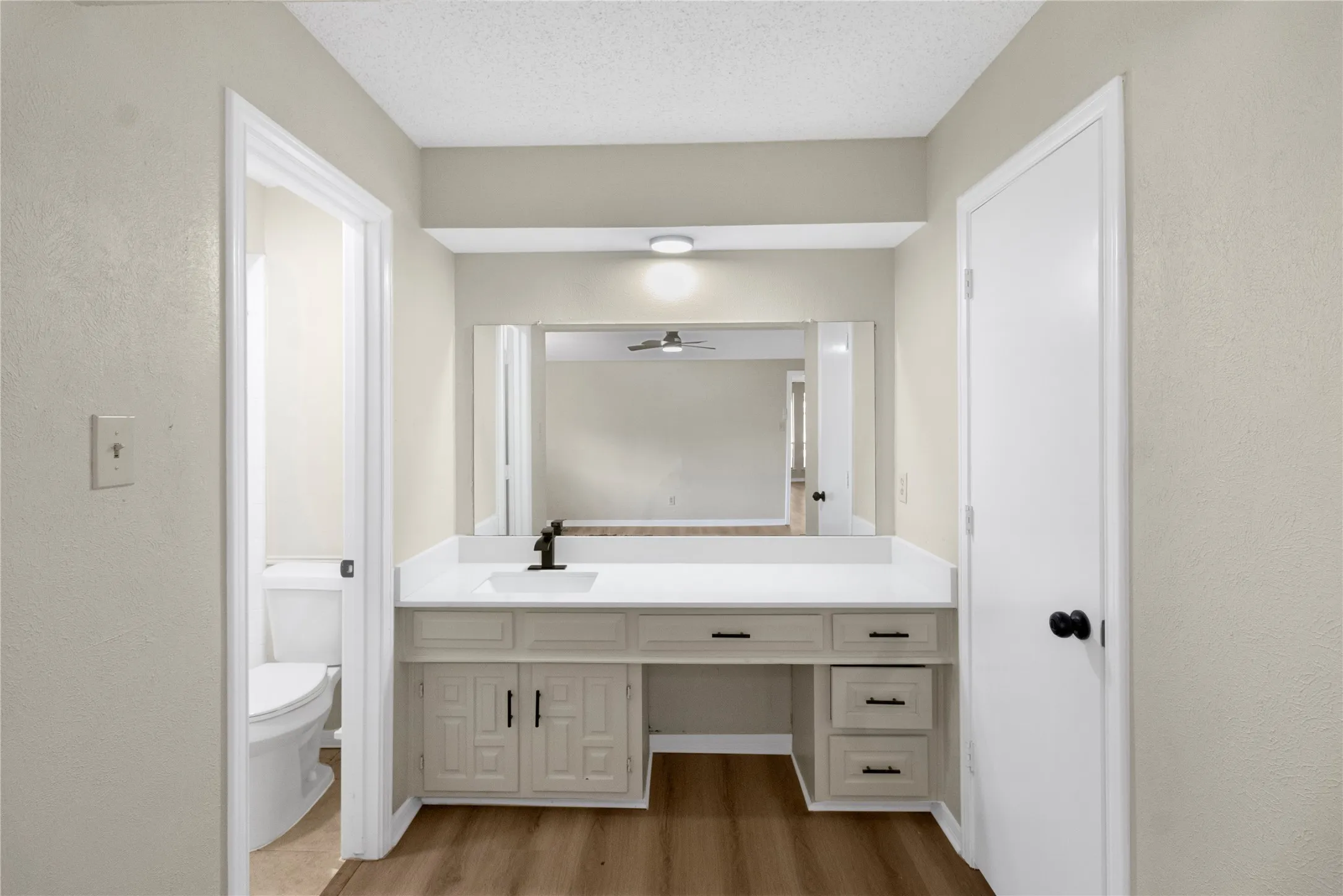 Vanity with a white countertop, under-mount sink, matte black faucet, and integrated storage