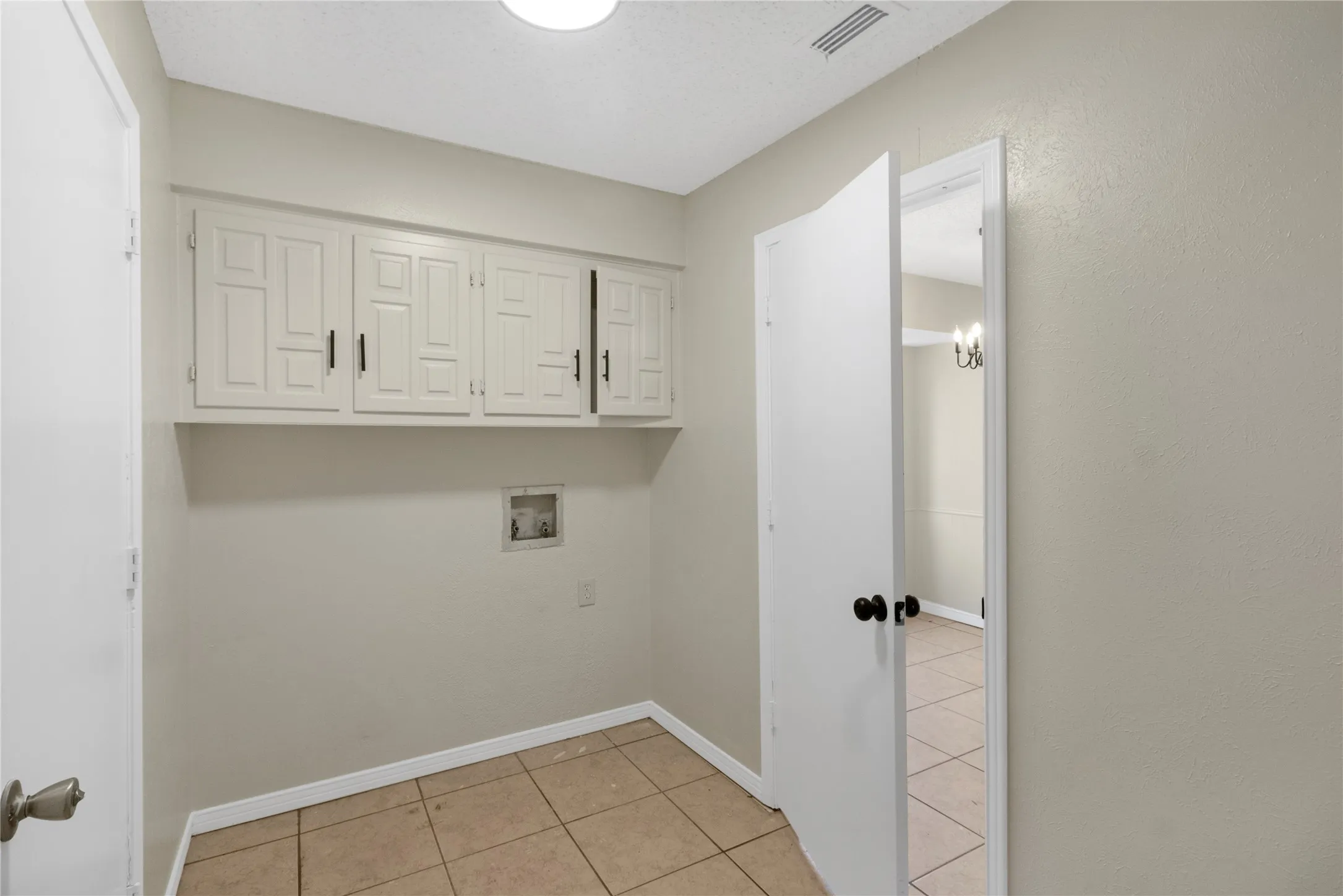 Built-in cabinetry with panel doors and matte black hardware, tile flooring, and wall-mounted light fixture