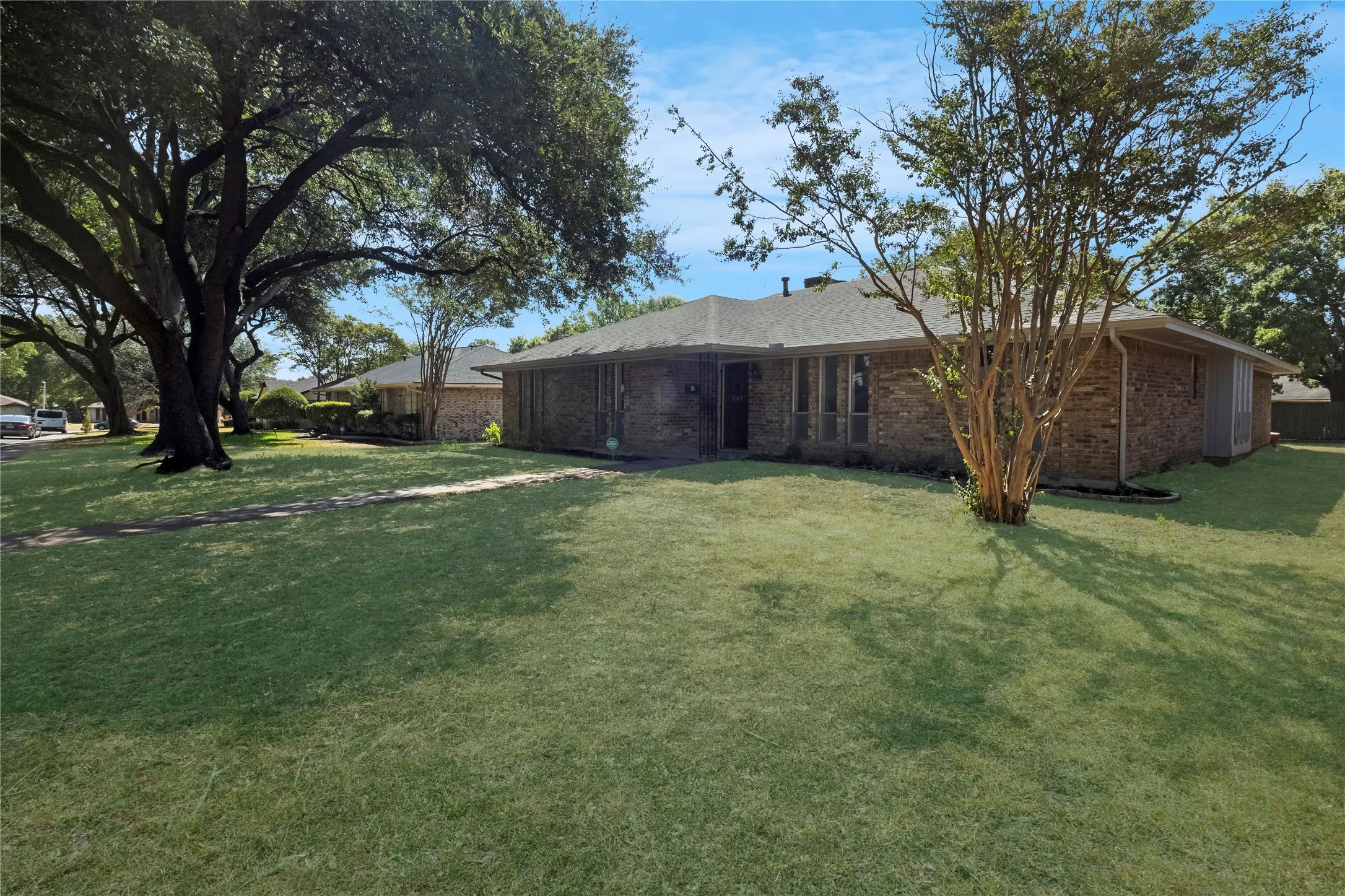 Brick exterior, gabled roof, mature landscaping, front yard, and a paved walkway leading to the entrance