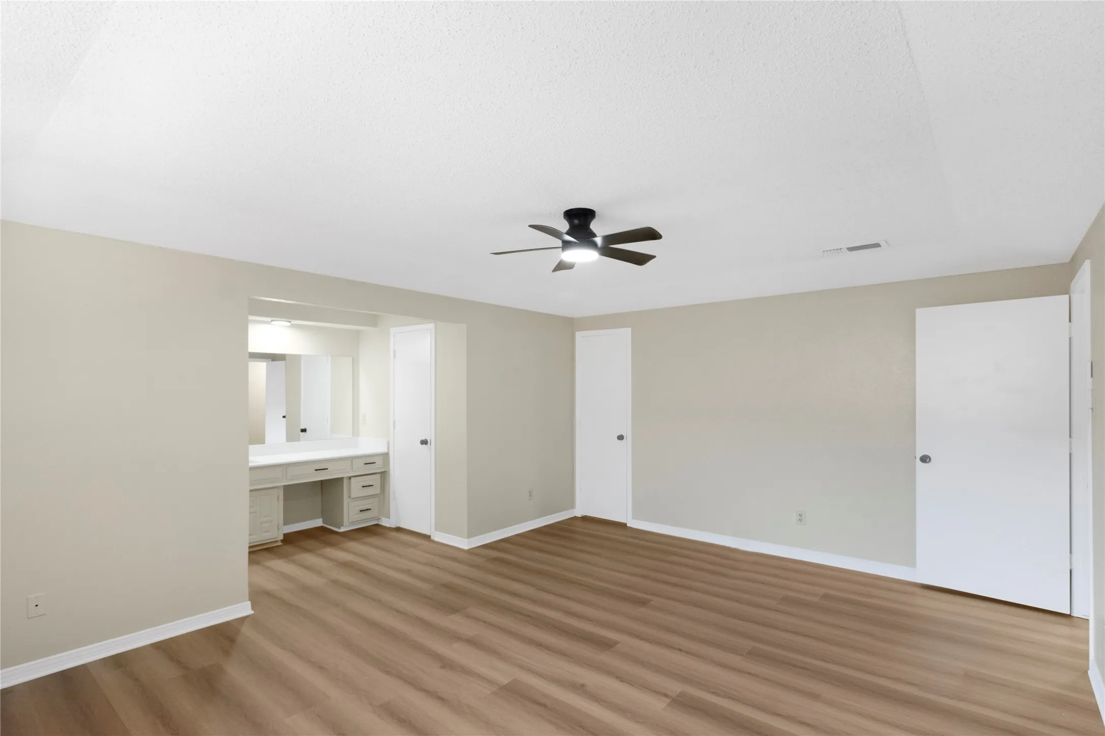 Wood-finish flooring, built-in vanity with mirror, built-in cabinetry with drawers, ceiling fan, and overhead lighting