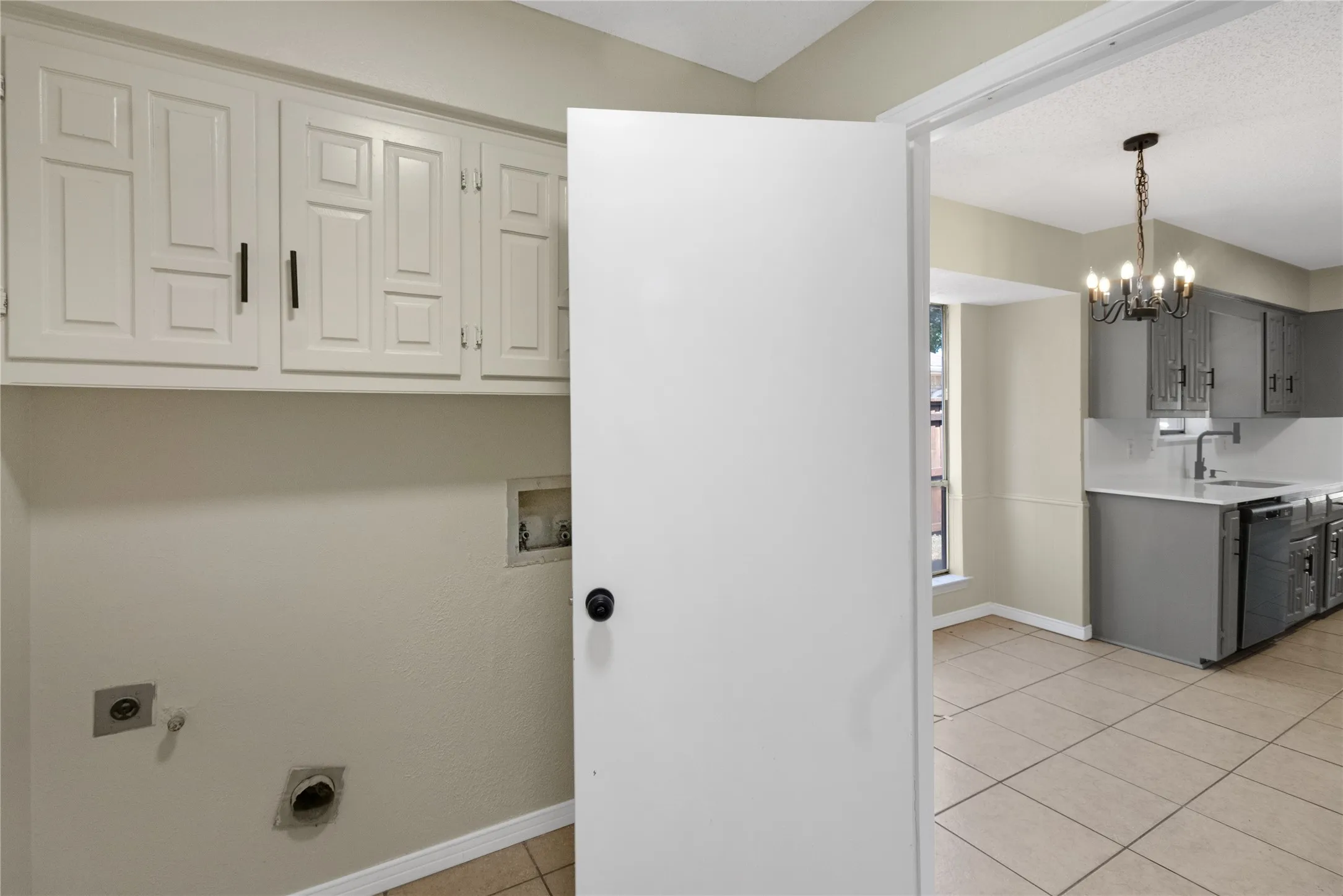 White cabinetry with black hardware, tile flooring, and neutral wall tones