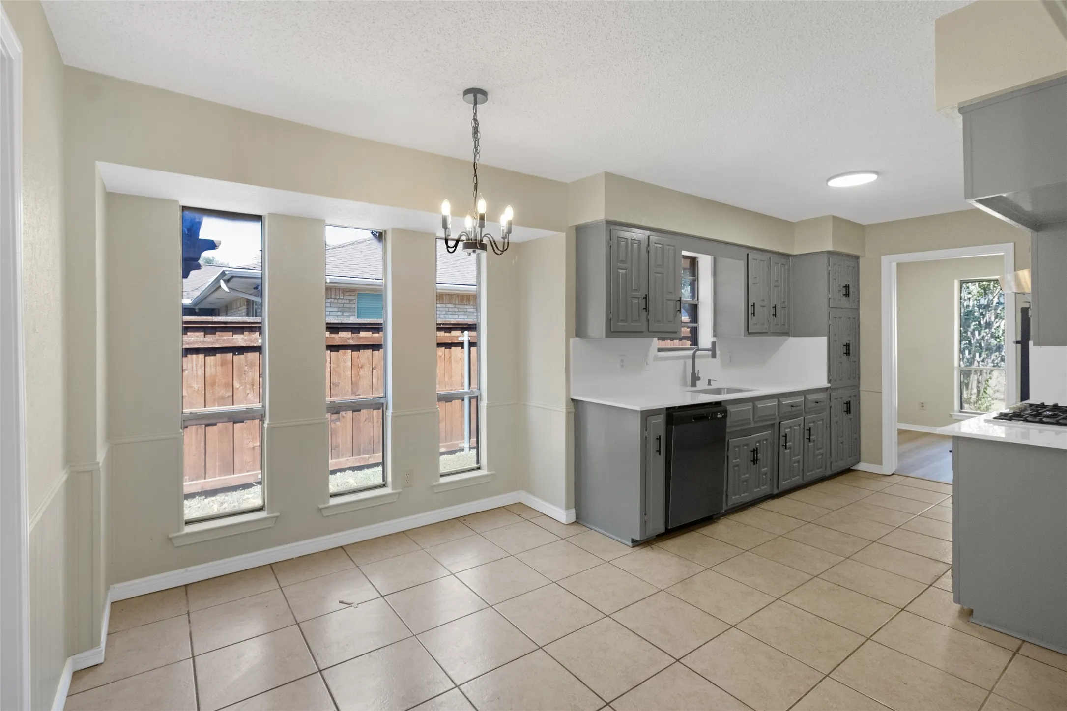 Kitchen and dining area featuring gray cabinetry, white countertops, tile flooring, and multiple windows