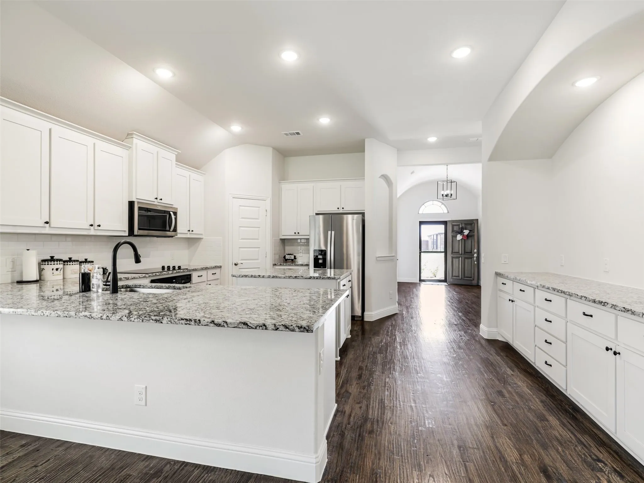 Kitchen featuring white cabinetry, granite countertops, stainless steel appliances, and wood-finish flooring