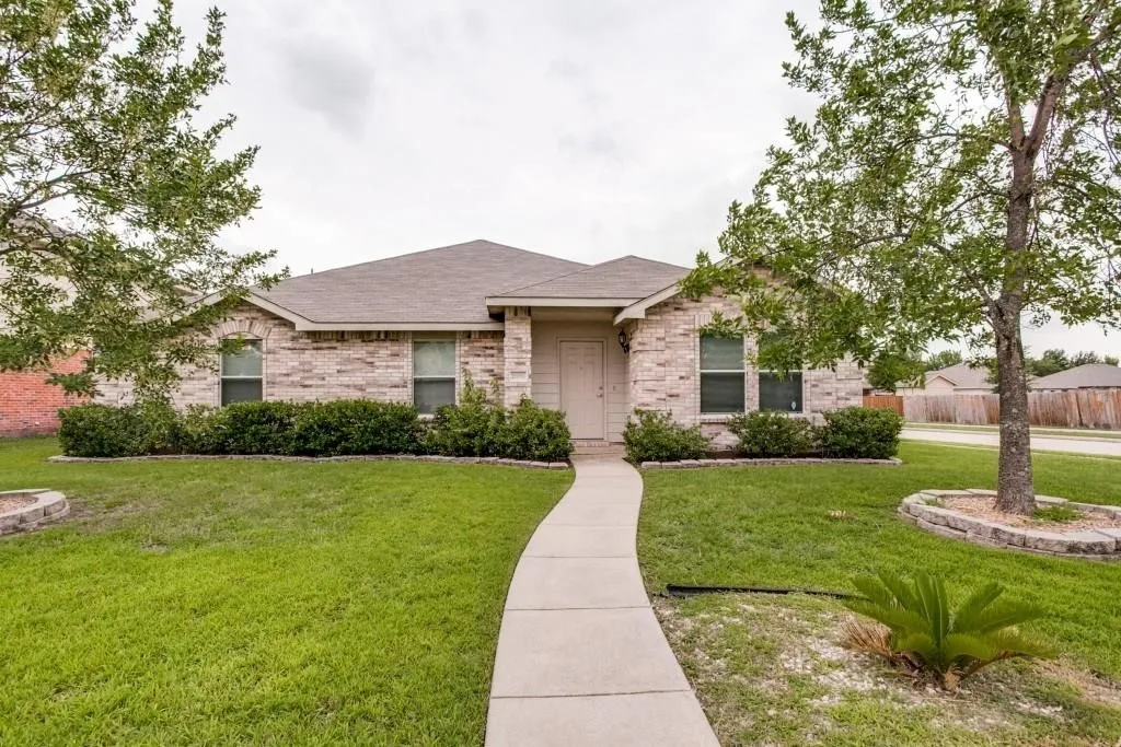 Brick facade residence with a gabled roof, front walkway, manicured lawn, and established landscaping