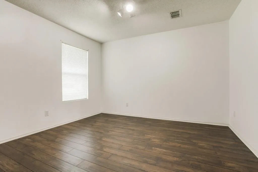 Wood-finish flooring, white walls, and a window with blinds