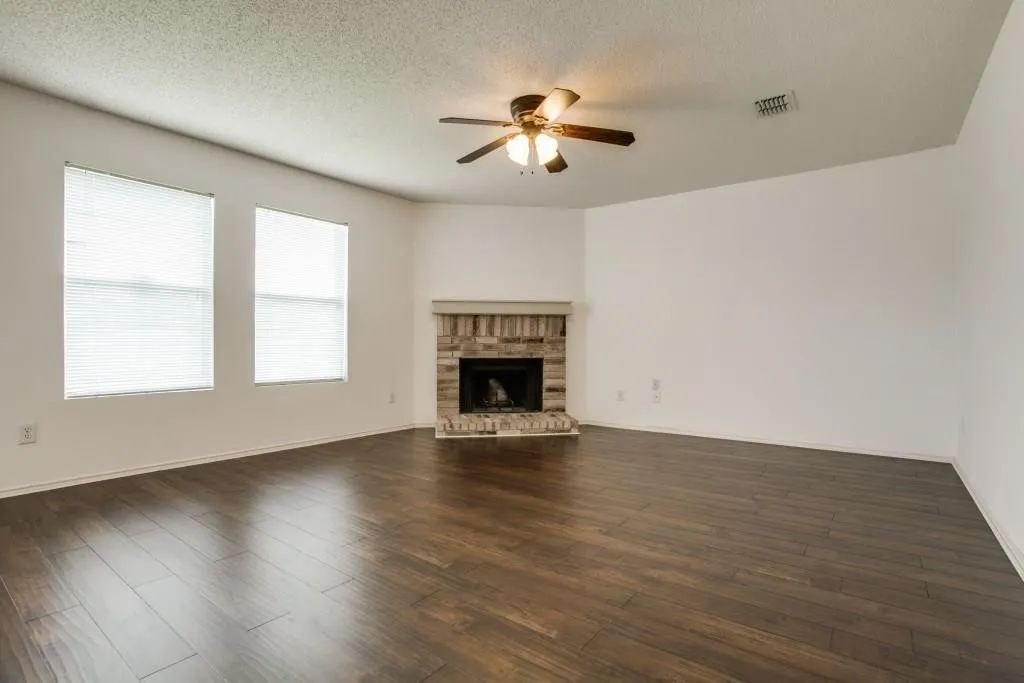 Wood-finish flooring throughout, featuring a brick fireplace
