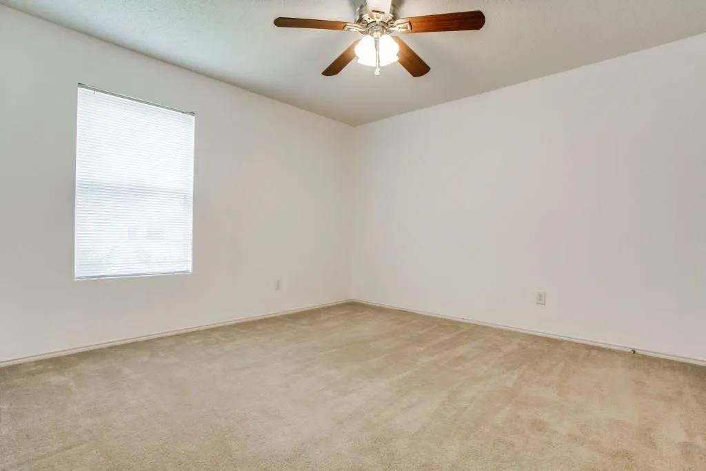 Recessed window with blinds, overhead ceiling fan with light fixture, light-colored carpeting, and painted walls