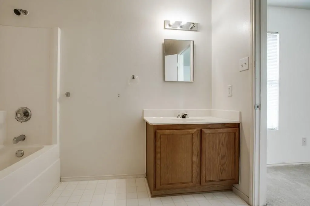 Built-in vanity with wood-finish cabinetry, white countertop, and integrated sink