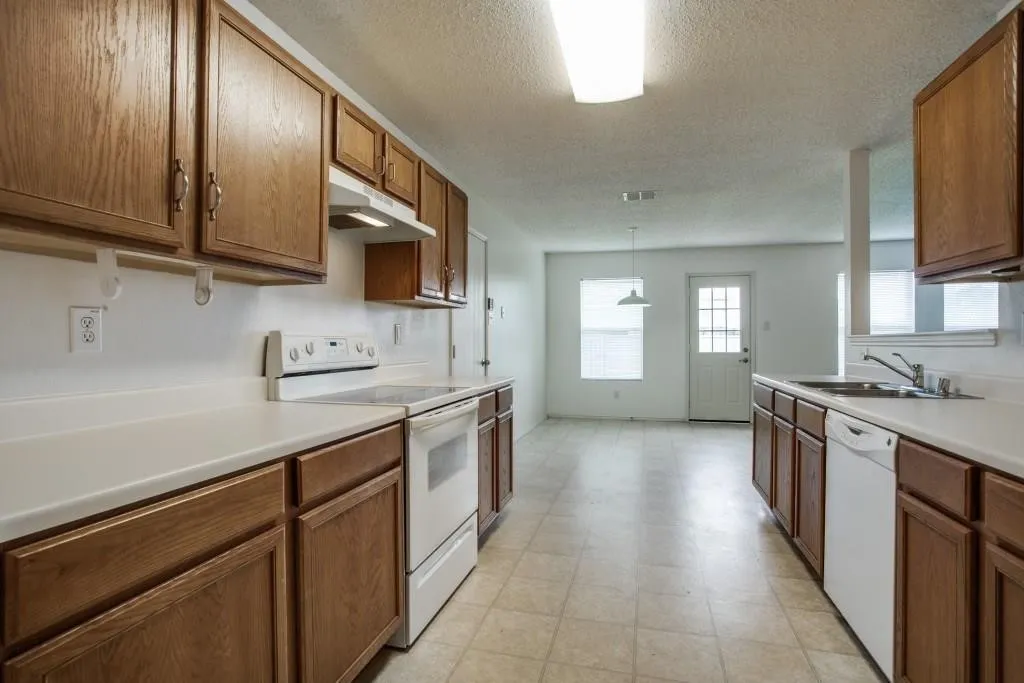 Kitchen featuring wood-finish cabinetry, white countertops, a white electric range, and a white dishwasher