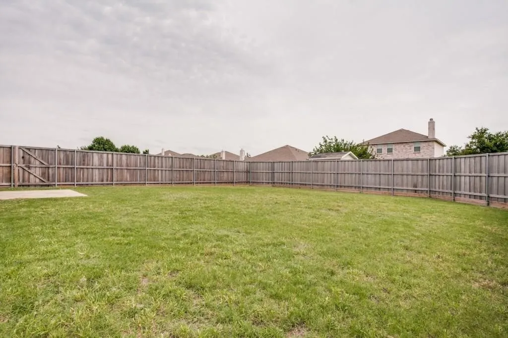 Expansive grass lawn bordered by a wood privacy fence with a gated entry