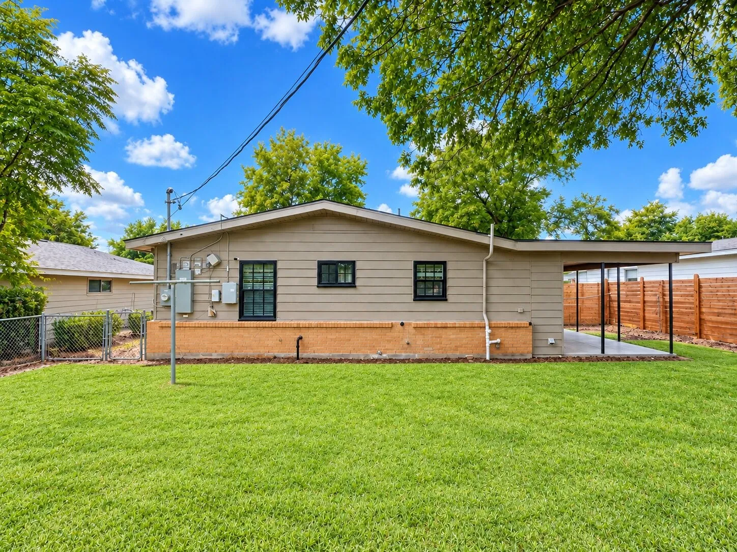 Expansive grass backyard with a chain-link fence and mature trees