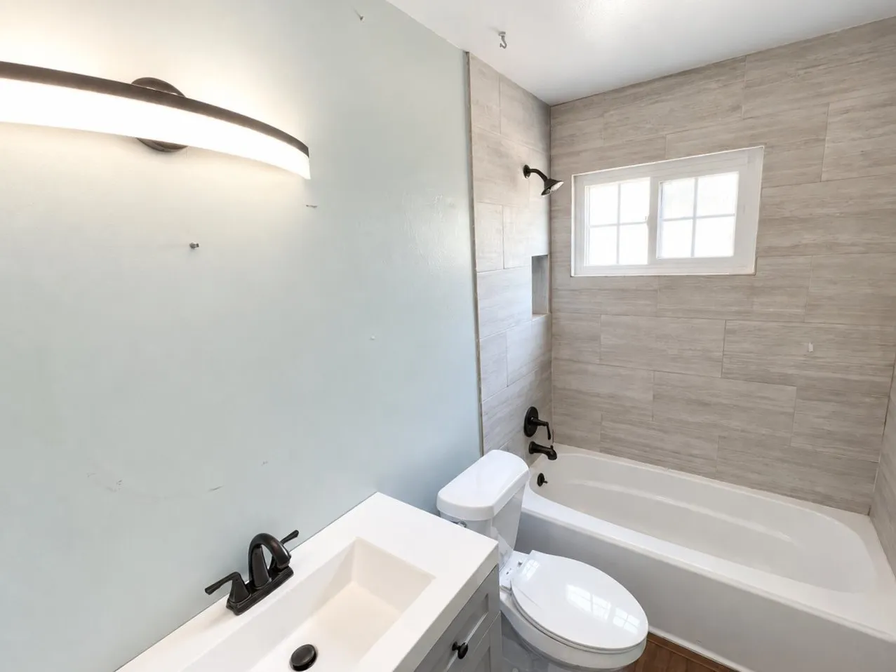 Virtually staged -
Modern vanity with integrated sink, matte black faucet, and contemporary light fixture