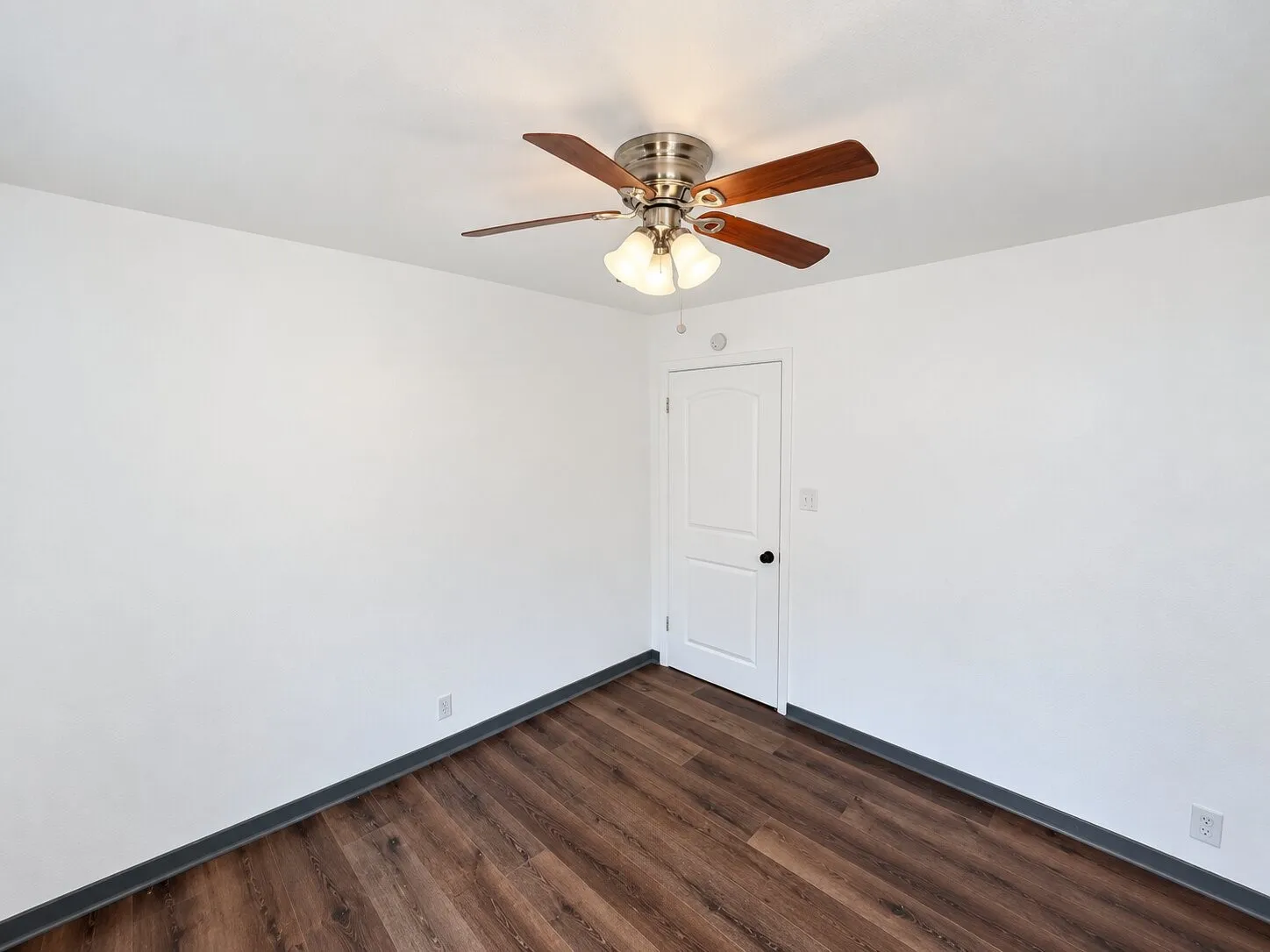 Virtually staged -
White interior walls, wood-finish flooring, ceiling fan with integrated lighting, paneled interior door, and a built-in wall mirror