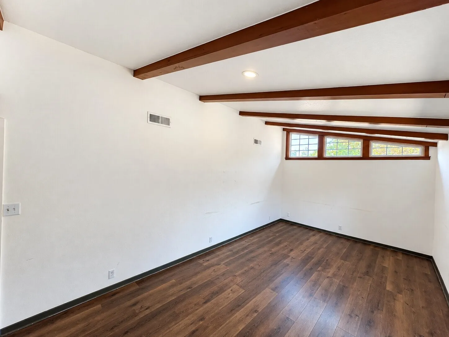 Vaulted ceiling with exposed wood beams, wood-finish flooring, recessed lighting, and multiple transom windows