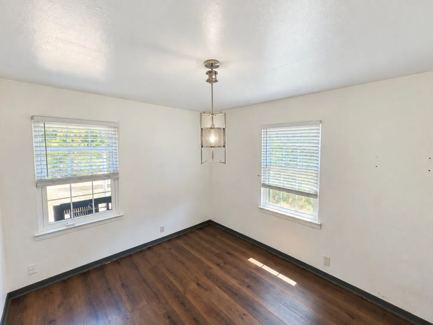 Virtually staged -
Wood-finish flooring, two windows with blinds, and a contemporary ceiling light fixture