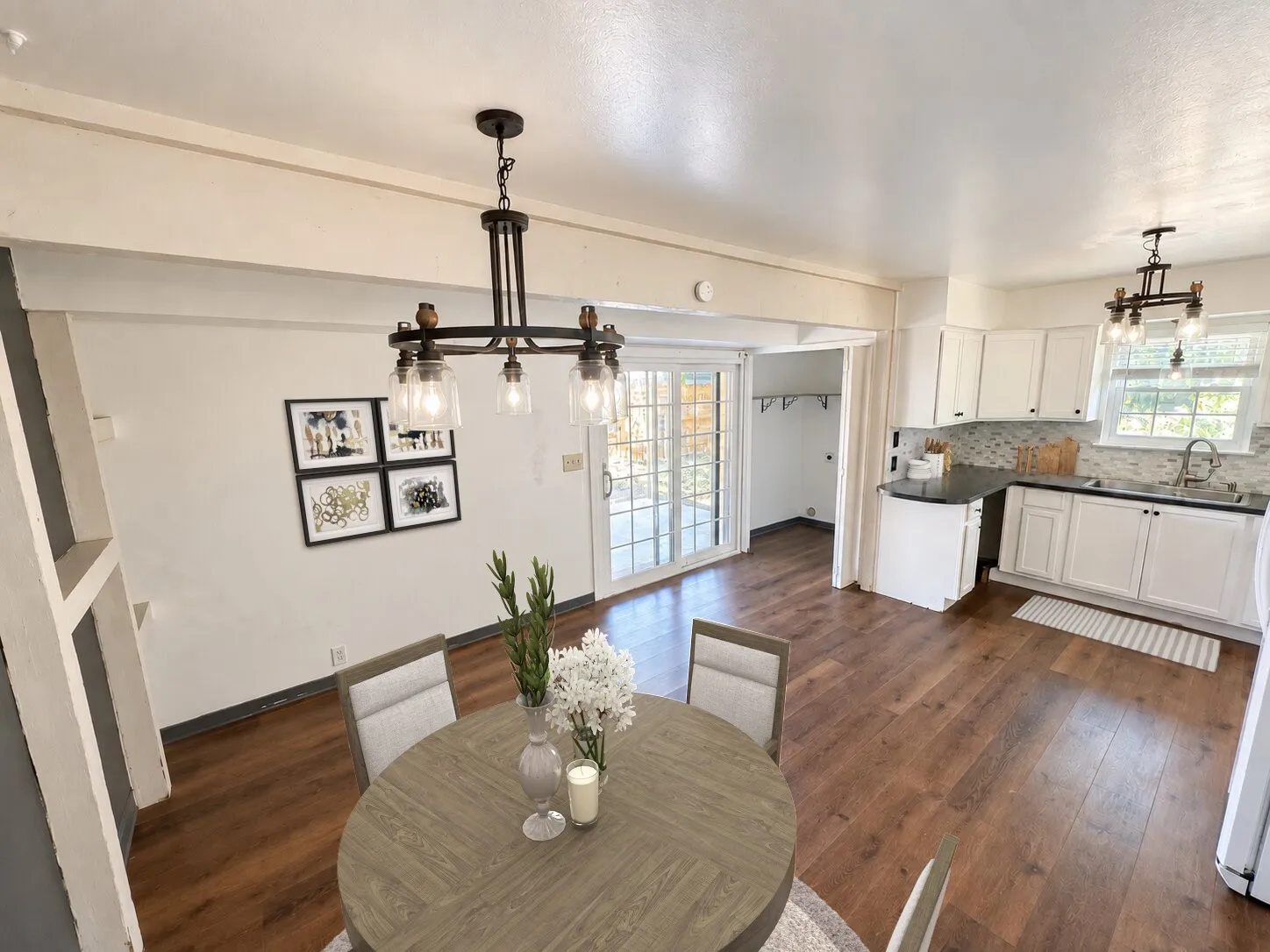 Virtually staged -
Wood-finish flooring, white cabinetry, dark countertops, tiled backsplash, and glass-paned sliding doors