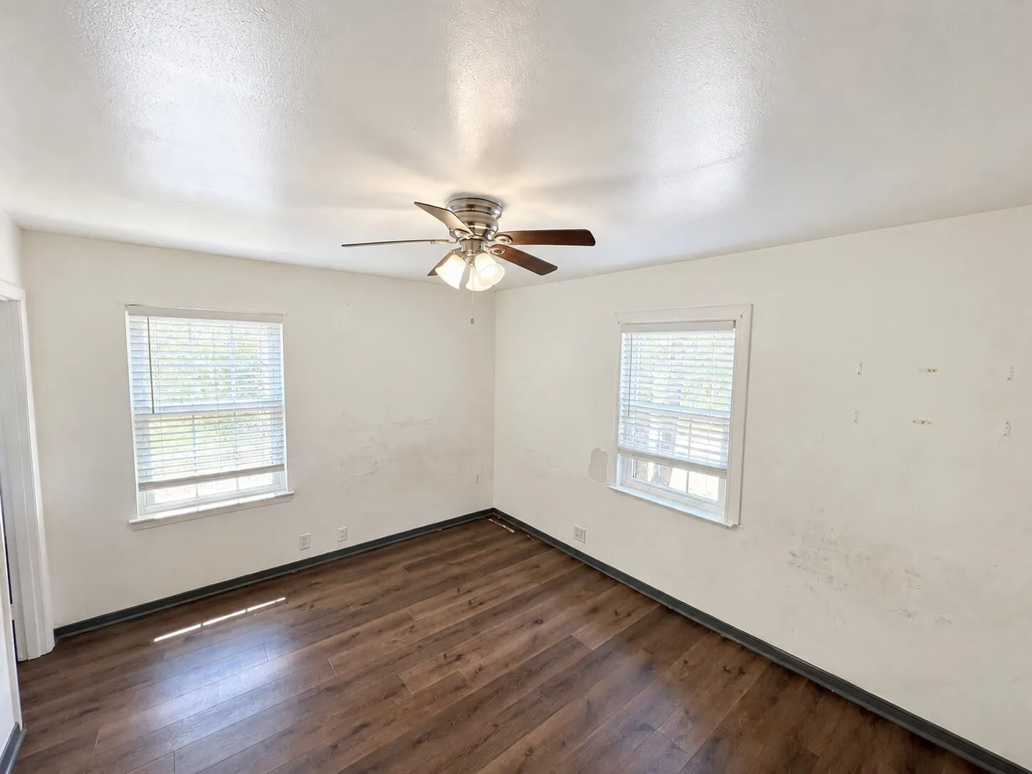 Virtually staged -
Wood-finish flooring, two windows with blinds, and a ceiling fan with integrated lighting