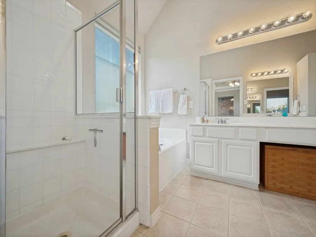 The spacious primary bath features dual sinks and vanities, a relaxing jetted tub, and a separate shower. A generous walk-in closet provides ample storage and completes this comfortable retreat.