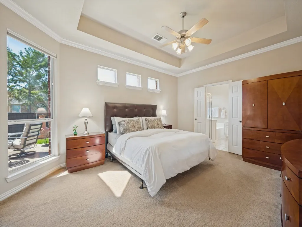 A generously sized primary suite welcomes you with abundant natural light, ample space for a king-size bed, and a cozy sitting area overlooking the back patio—creating a peaceful retreat at the end of the day.