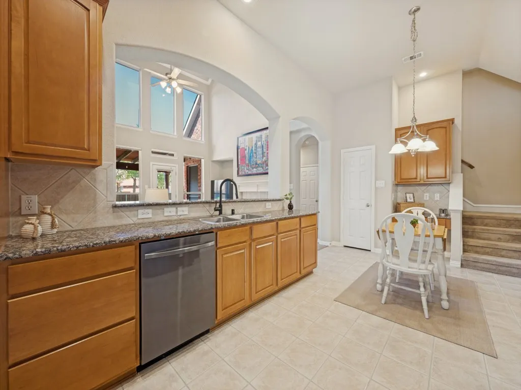 Designed for both functionality and flow, the open kitchen features cherry cabinets, granite countertops, black appliances, and a gas cooktop, with an easy connection to the adjoining living spaces.