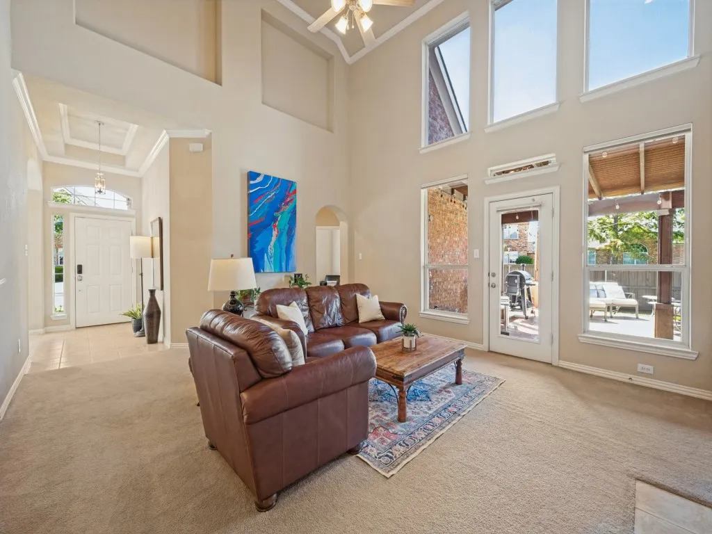 The inviting living room features a wall of windows that fills the space with beautiful natural light, creating a bright and welcoming atmosphere throughout the home.