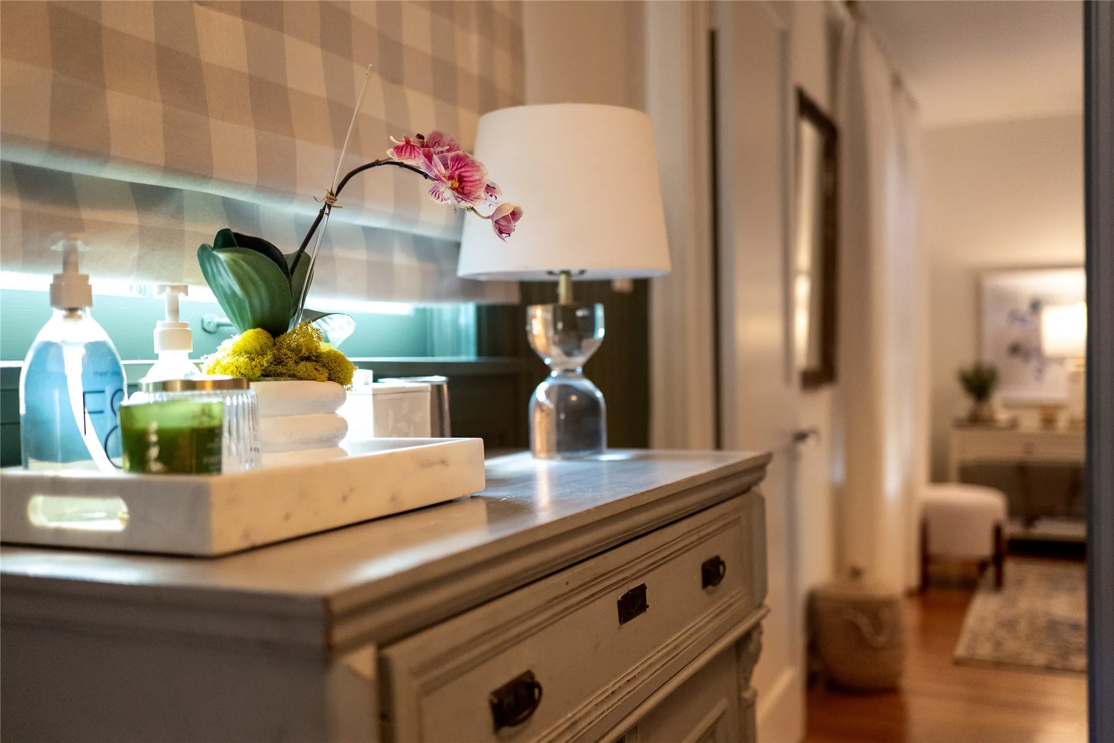 Distressed wood-finish dresser with drawers and cabinet doors, paired with a clear glass table lamp