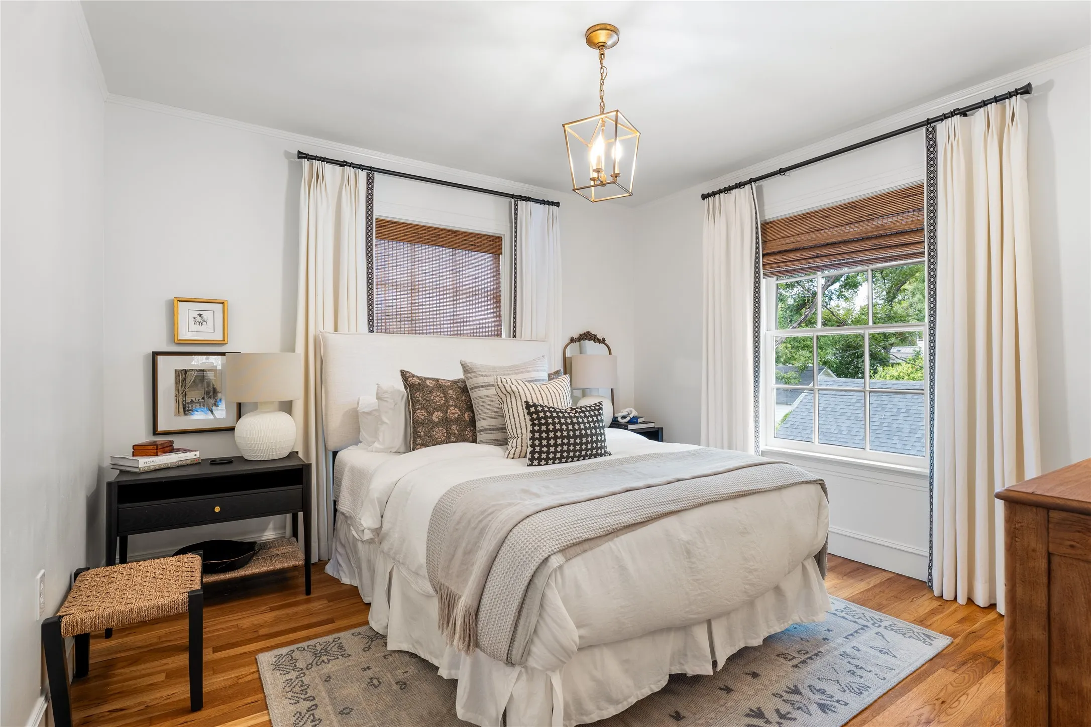 Hardwood flooring, dual windows with woven shades, a ceiling-mounted lantern light fixture, and a built-in wall niche